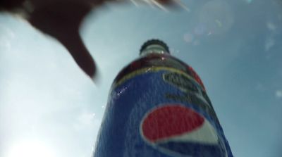 a close up of a pepsi bottle with the sky in the background