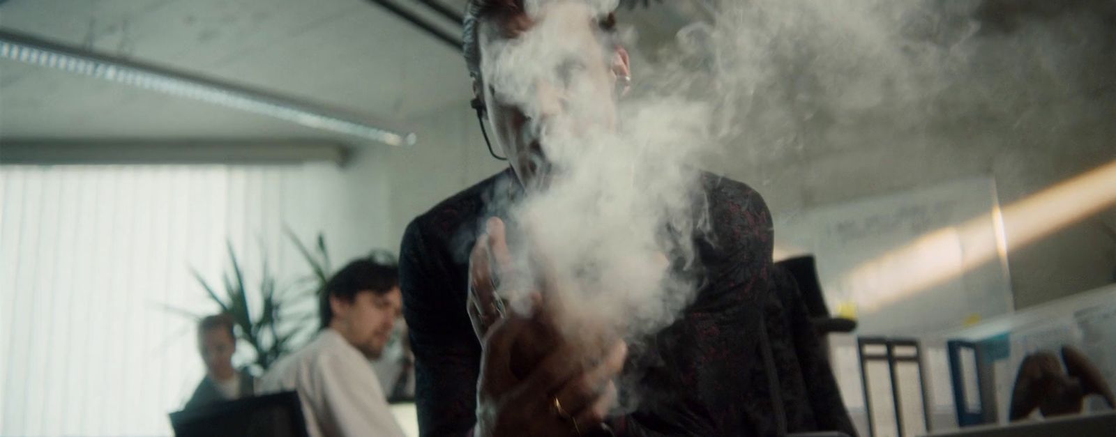 a man standing in front of a laptop computer covered in smoke