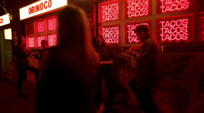 a group of people standing outside of a taco shop