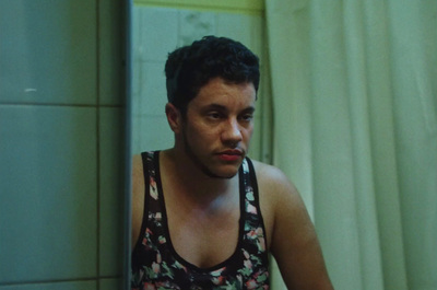 a man in a tank top standing in front of a mirror