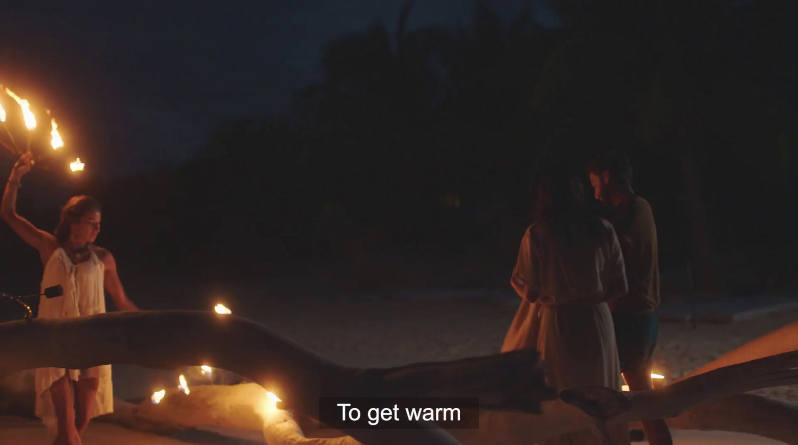 a group of people standing on a beach holding candles