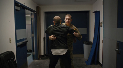 a couple of men standing next to each other in a hallway