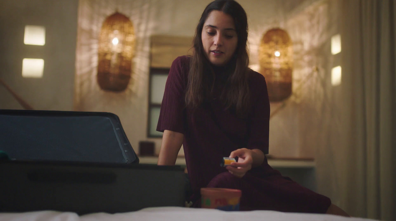 a woman sitting on a bed holding a remote control