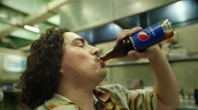 a woman in a kitchen drinking from a soda bottle