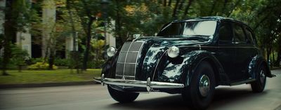 a black car driving down a street next to trees