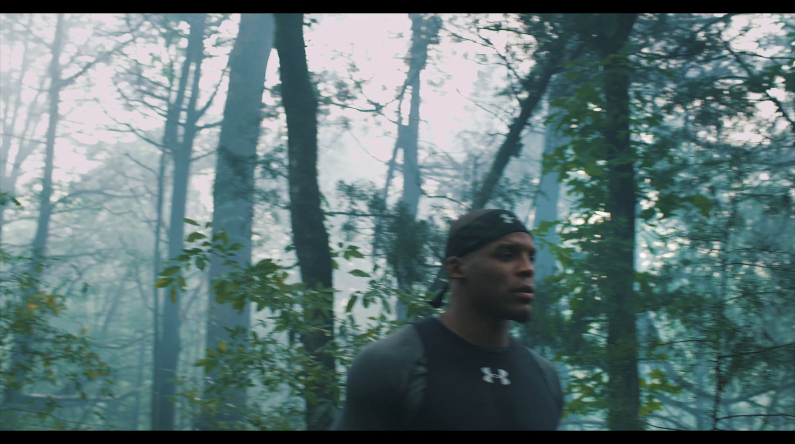 a man standing in a forest with trees in the background