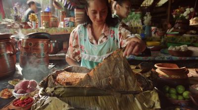 a woman preparing food on a table in a kitchen