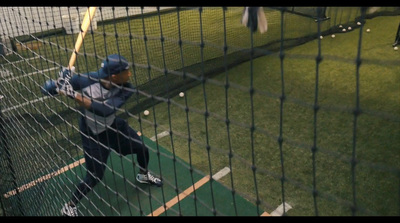 a man holding a baseball bat in a batting cage