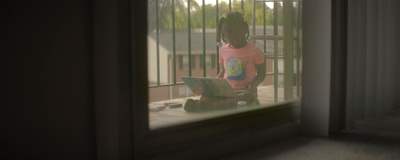 a young girl sitting on a porch using a laptop computer