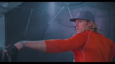 a woman in an orange shirt holding a baseball glove