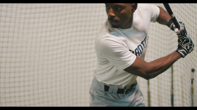 a man holding a baseball bat in a batting cage