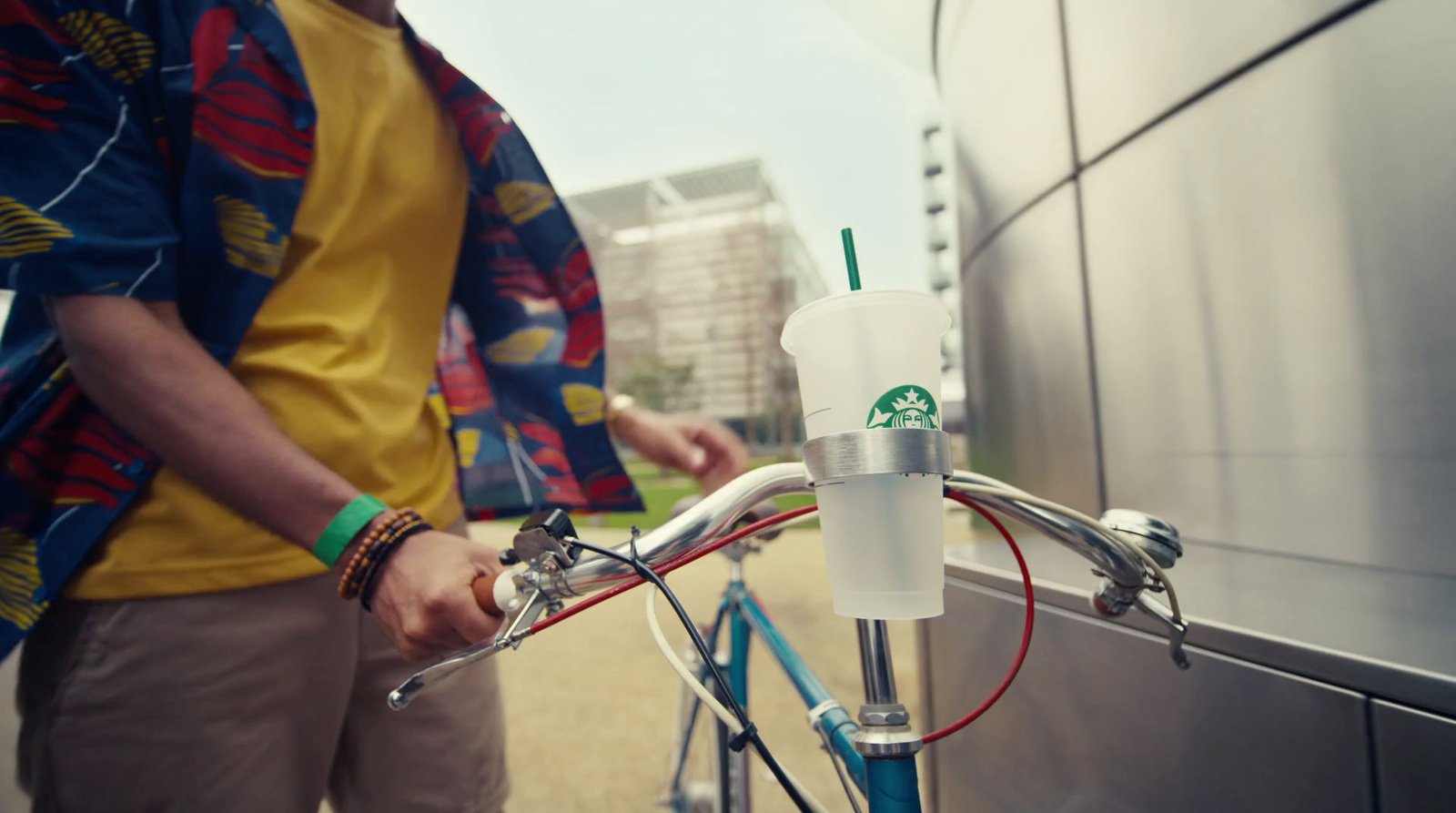 a man is holding a starbucks cup on a bicycle