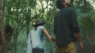 a man and a woman walking through a forest