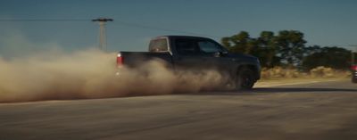 a truck driving down a road with dust behind it