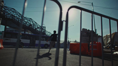 a man riding a skateboard past a metal fence