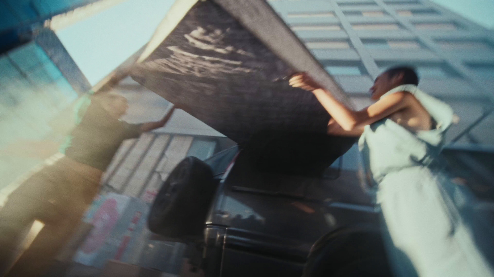 a woman standing next to a black car in front of a tall building