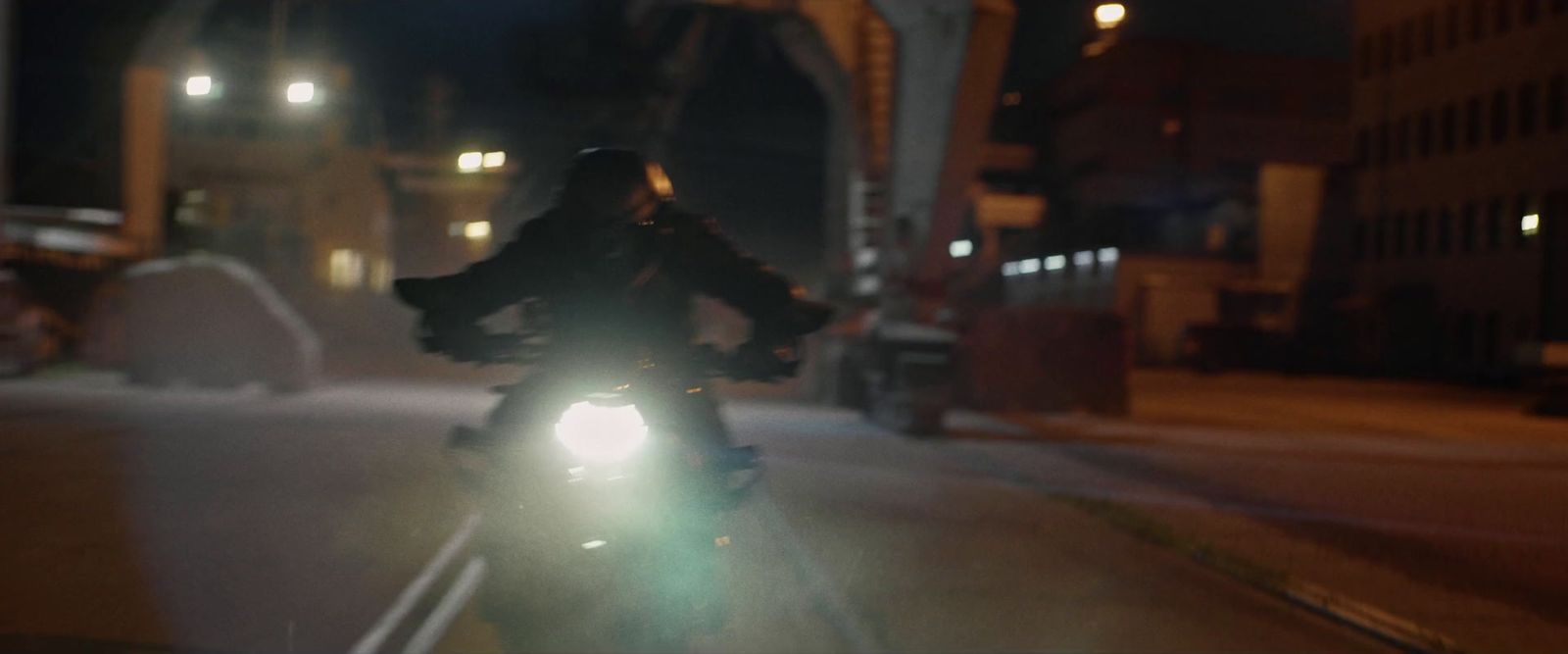 a person riding a motorcycle down a street at night