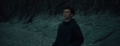 a man in a black hoodie standing in a cave