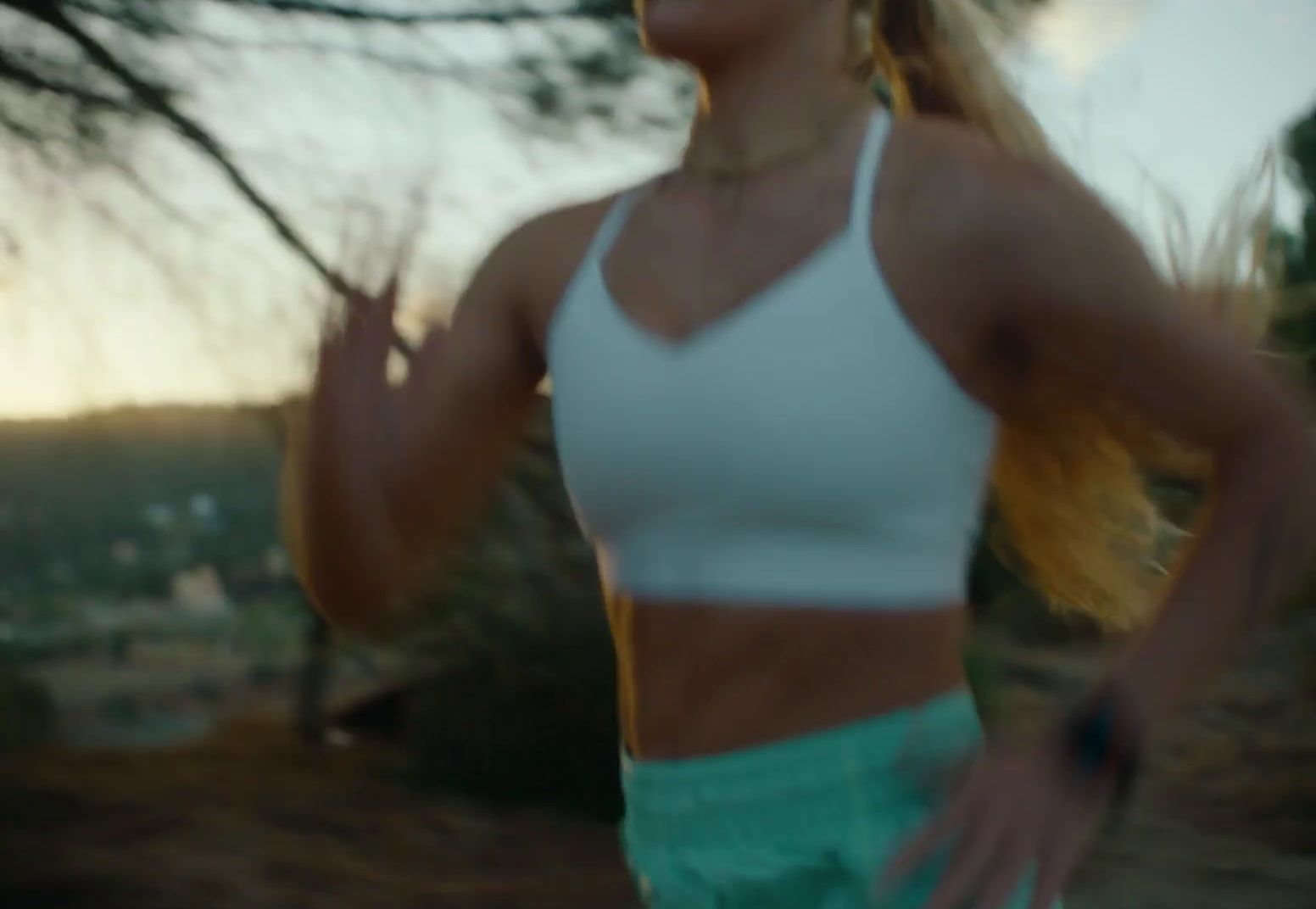 a woman in a white tank top and green shorts