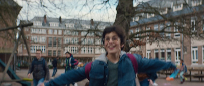 a boy with a backpack is running in a park