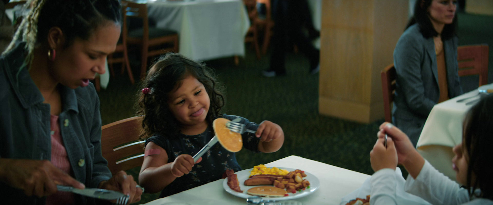 a young girl is eating breakfast with her family