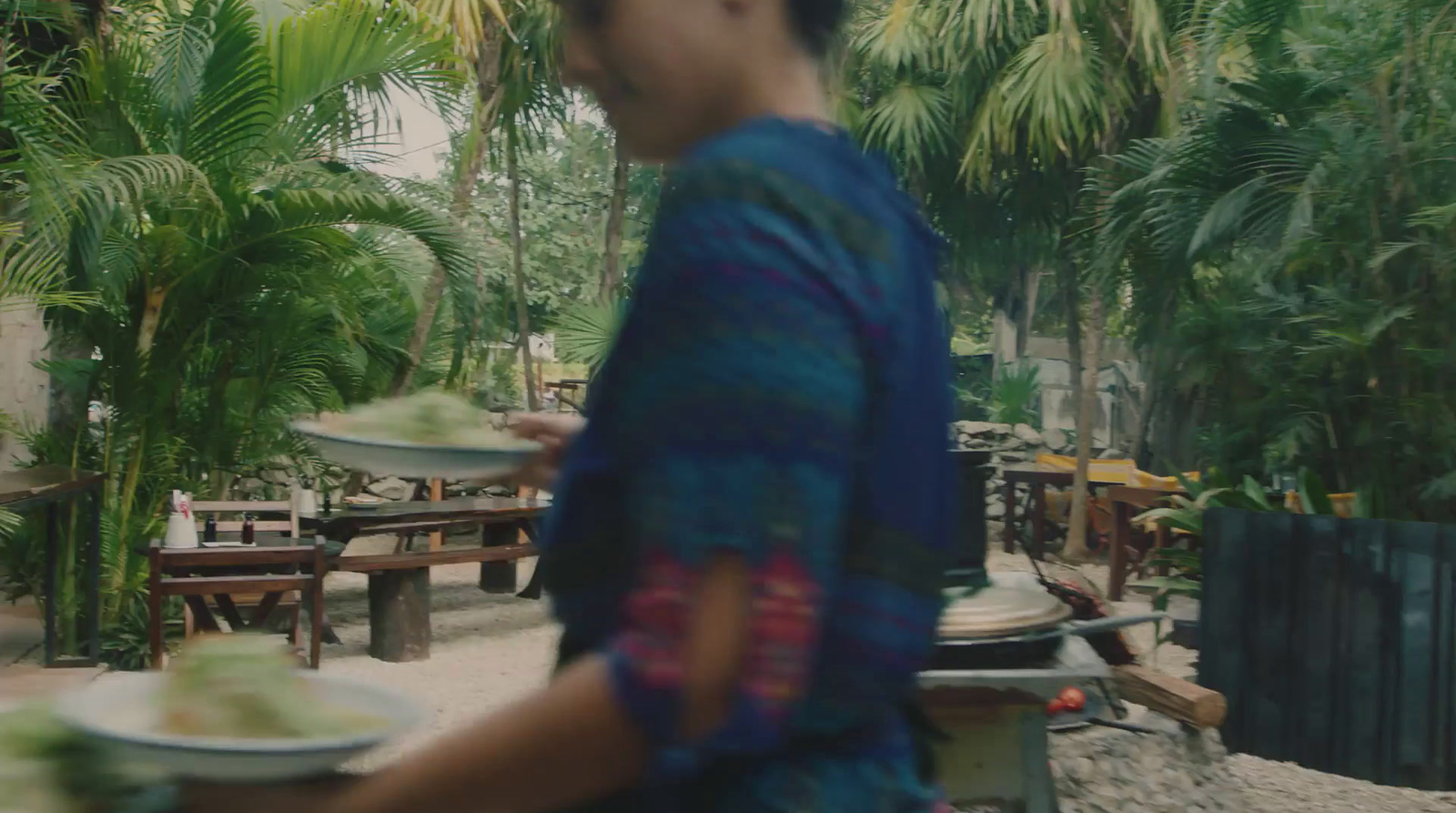 a woman carrying a plate of food in a tropical setting