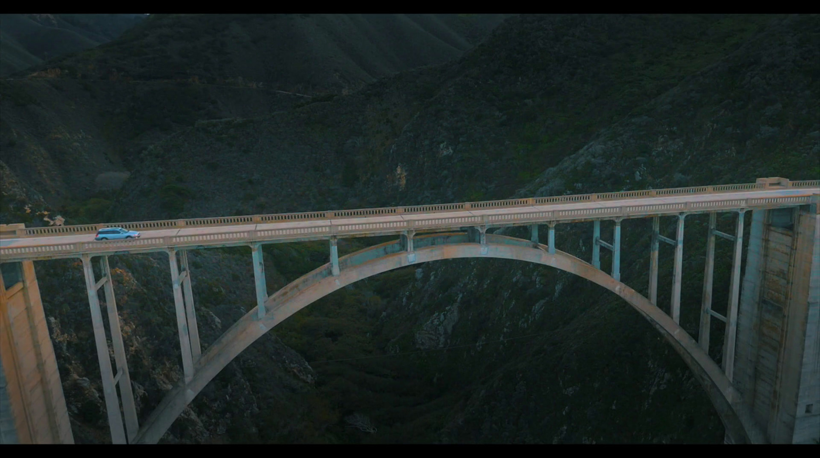 a car is driving over a bridge in the mountains