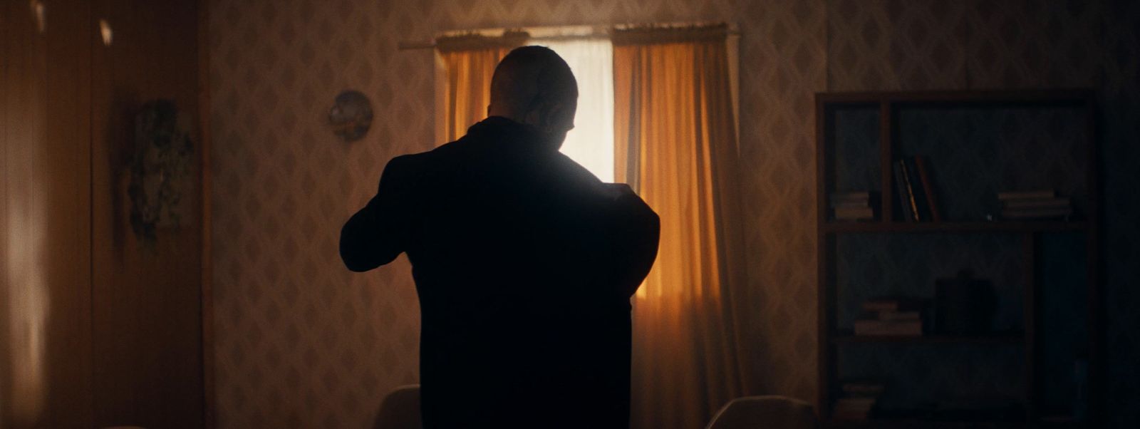 a man standing in a dark room with his back to the camera