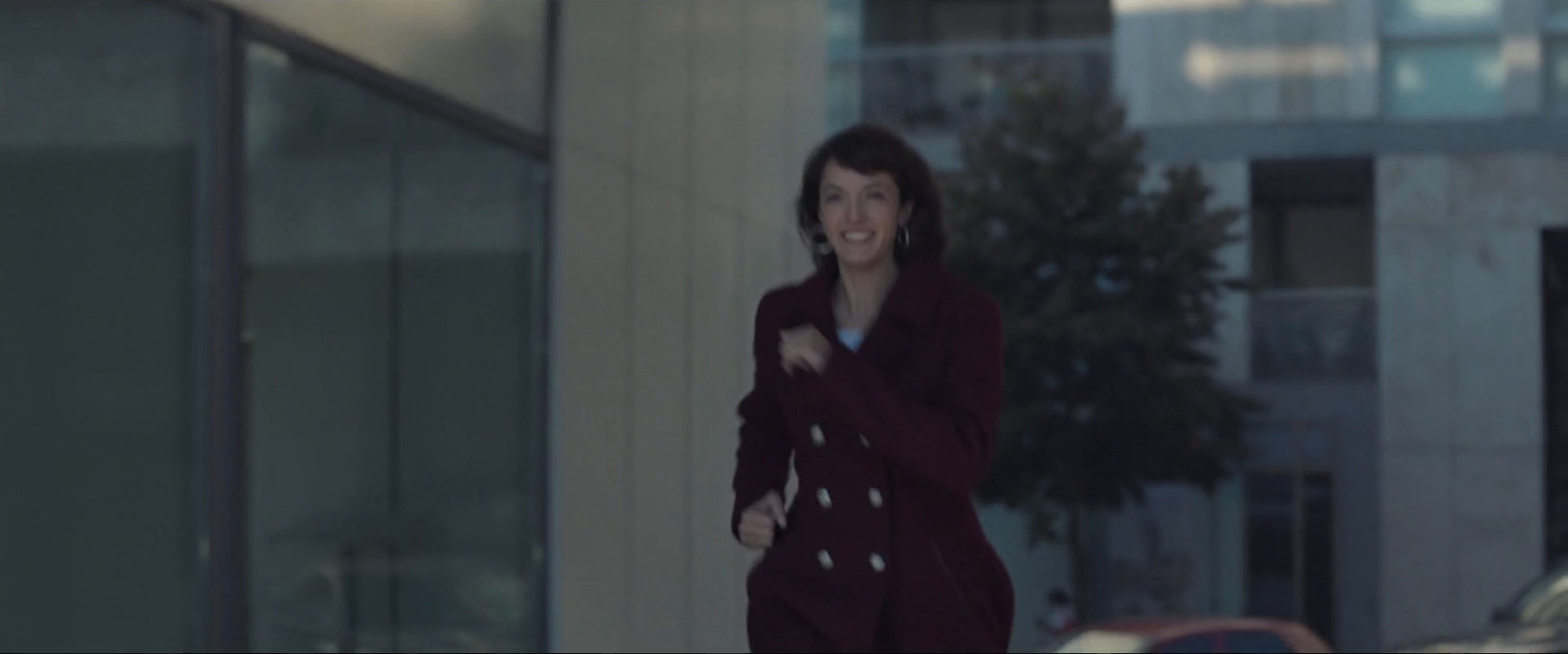 a woman walking down a street next to a tall building