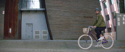 a man riding a bike down a street next to a tall building