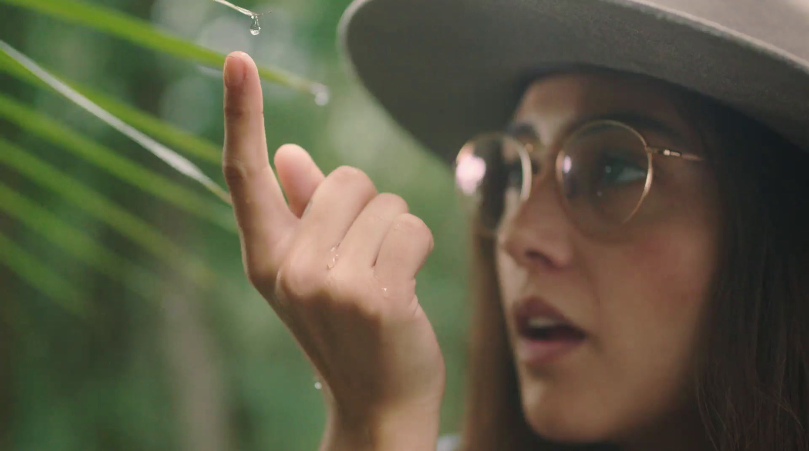 a woman wearing a hat and glasses holding a pair of scissors