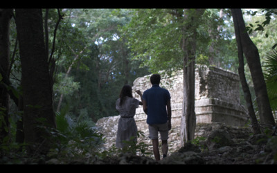 a man and a woman walking through a forest