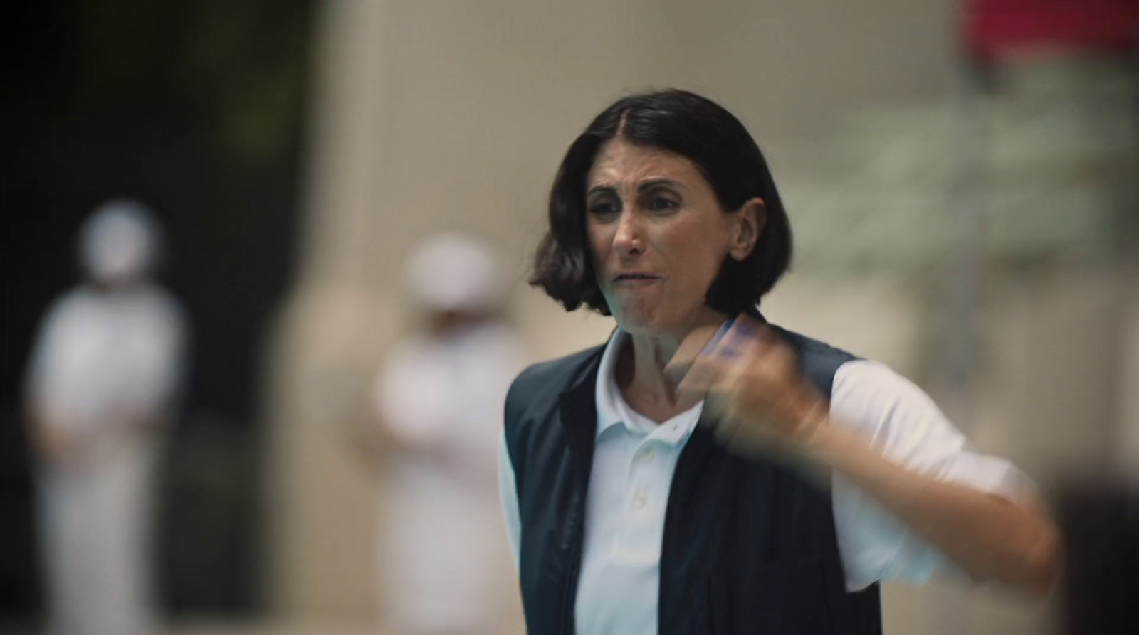 a woman in a white shirt and black vest holding a white frisbee