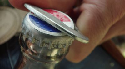 a close up of a person holding a bottle opener