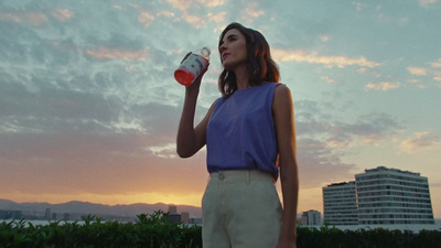 a woman in a blue top drinking from a can