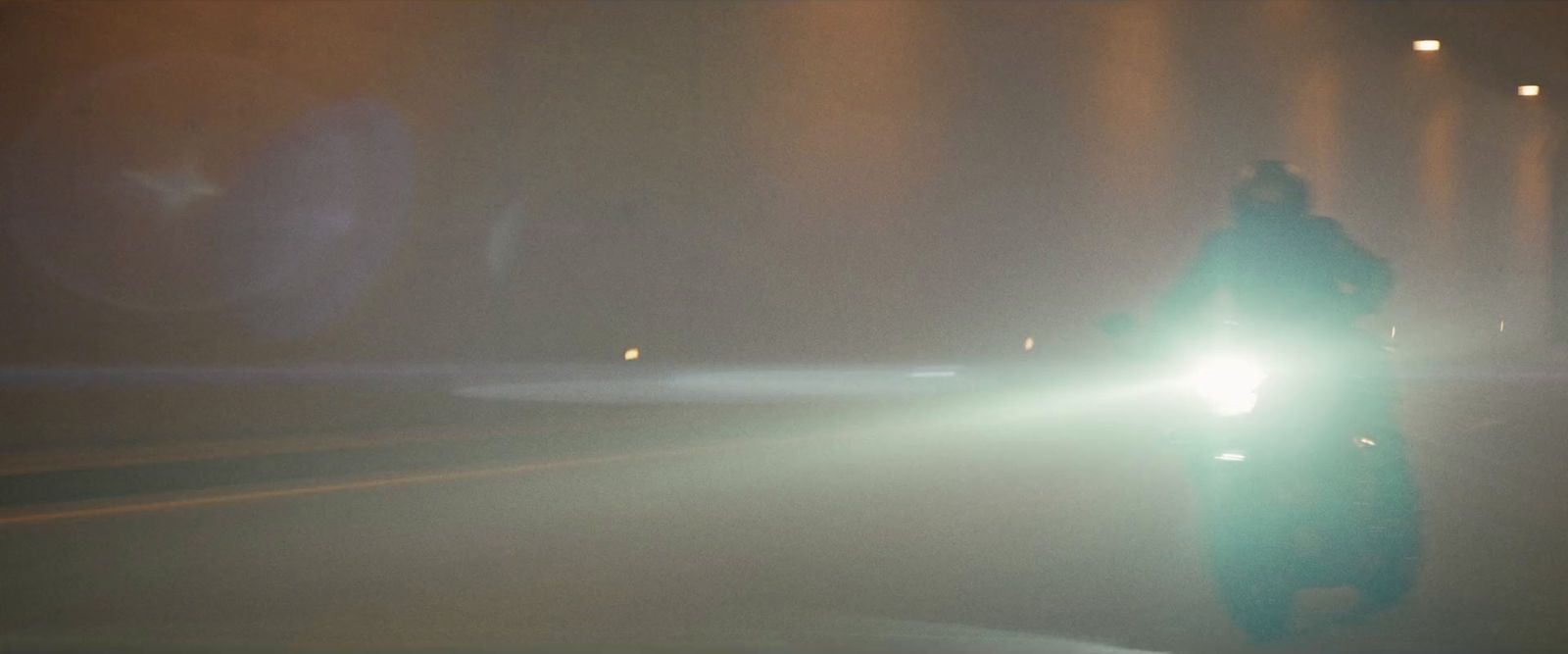 a man riding a motorcycle down a street at night