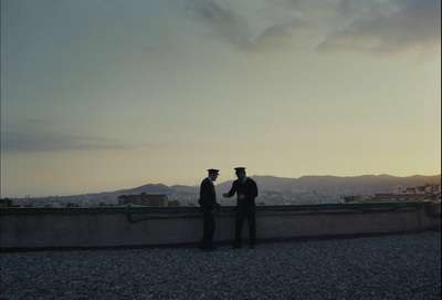 two men standing on top of a roof at sunset