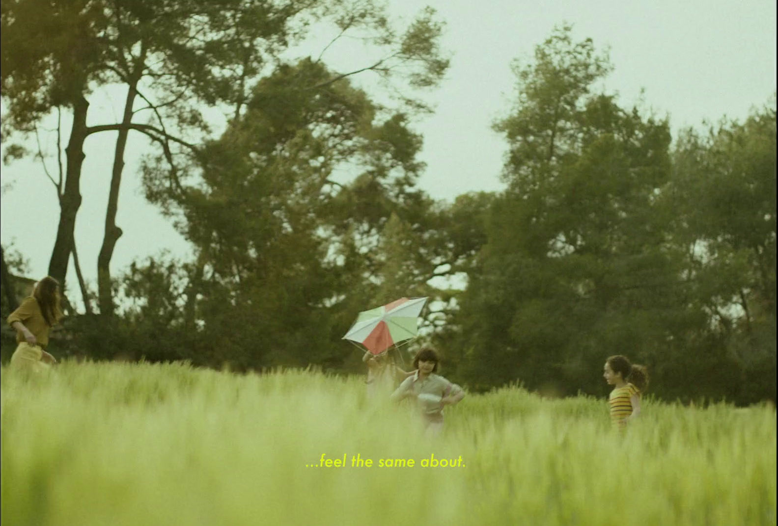 a group of people standing in a field with an umbrella