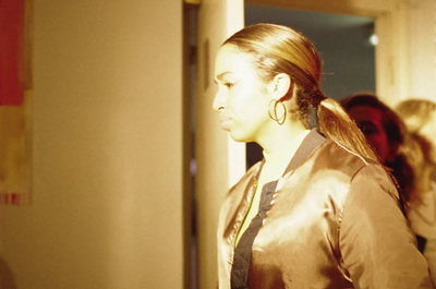 a woman in a brown jacket standing next to a door