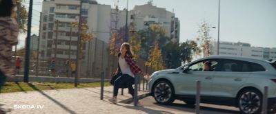 a woman walking down a sidewalk next to a car