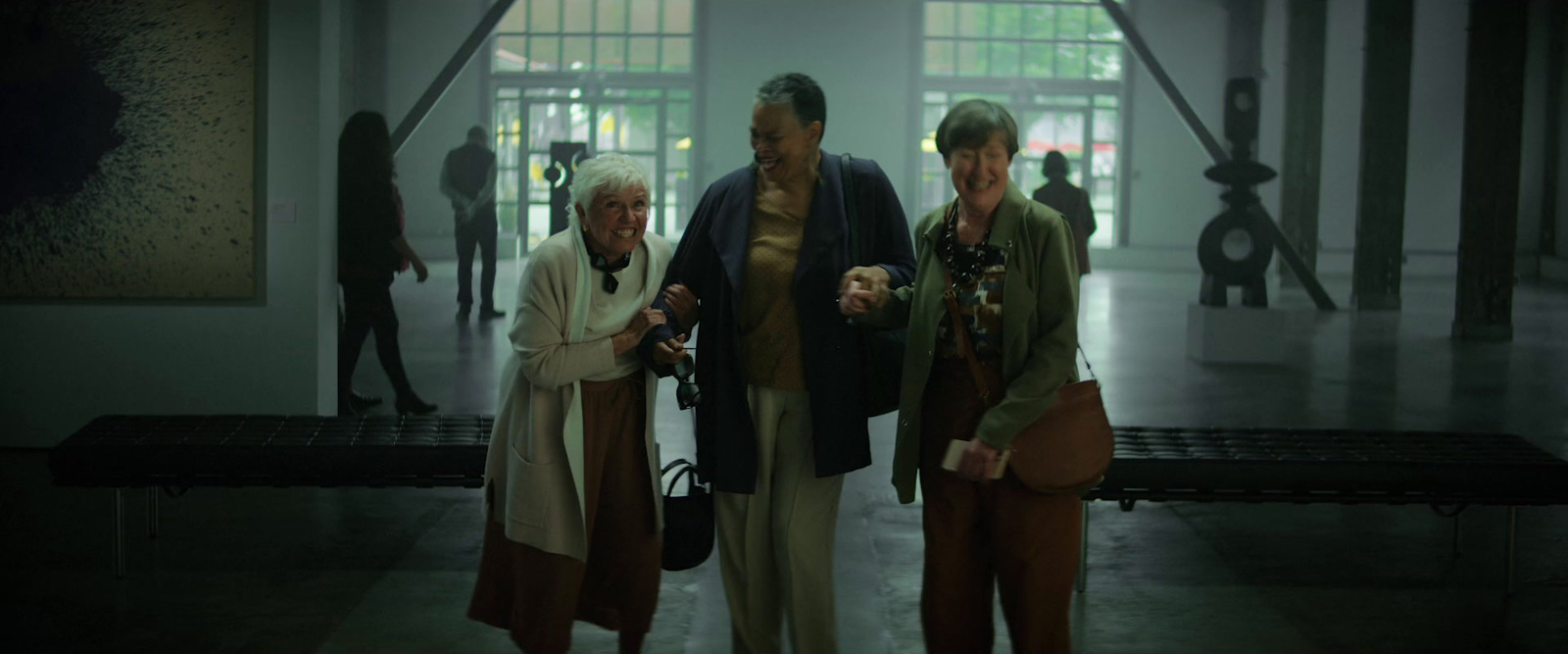 three women standing next to each other in an art gallery