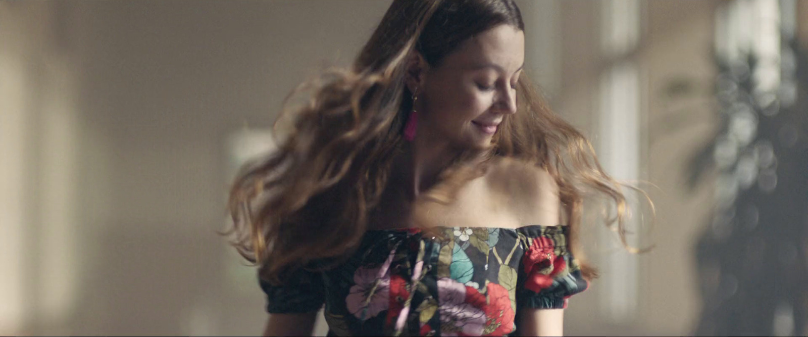 a woman with long hair walking down a hallway