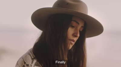 a woman with long hair wearing a brown hat