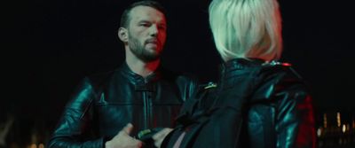 a man in a leather jacket talking to a woman