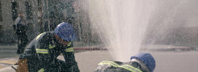 two firemen spraying water from a hose