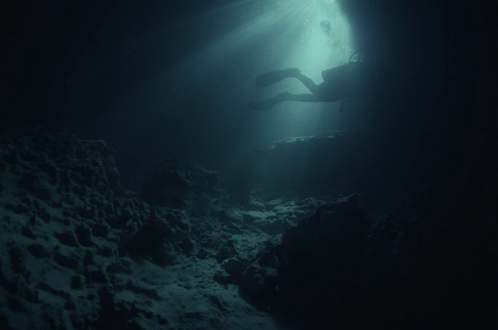 a person swimming in the water in a cave