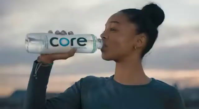 a woman drinking a bottle of core water