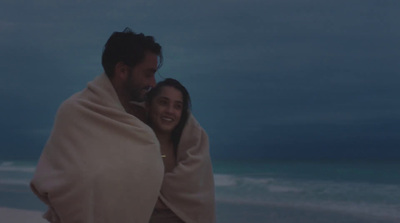 a man and woman wrapped in a blanket on the beach