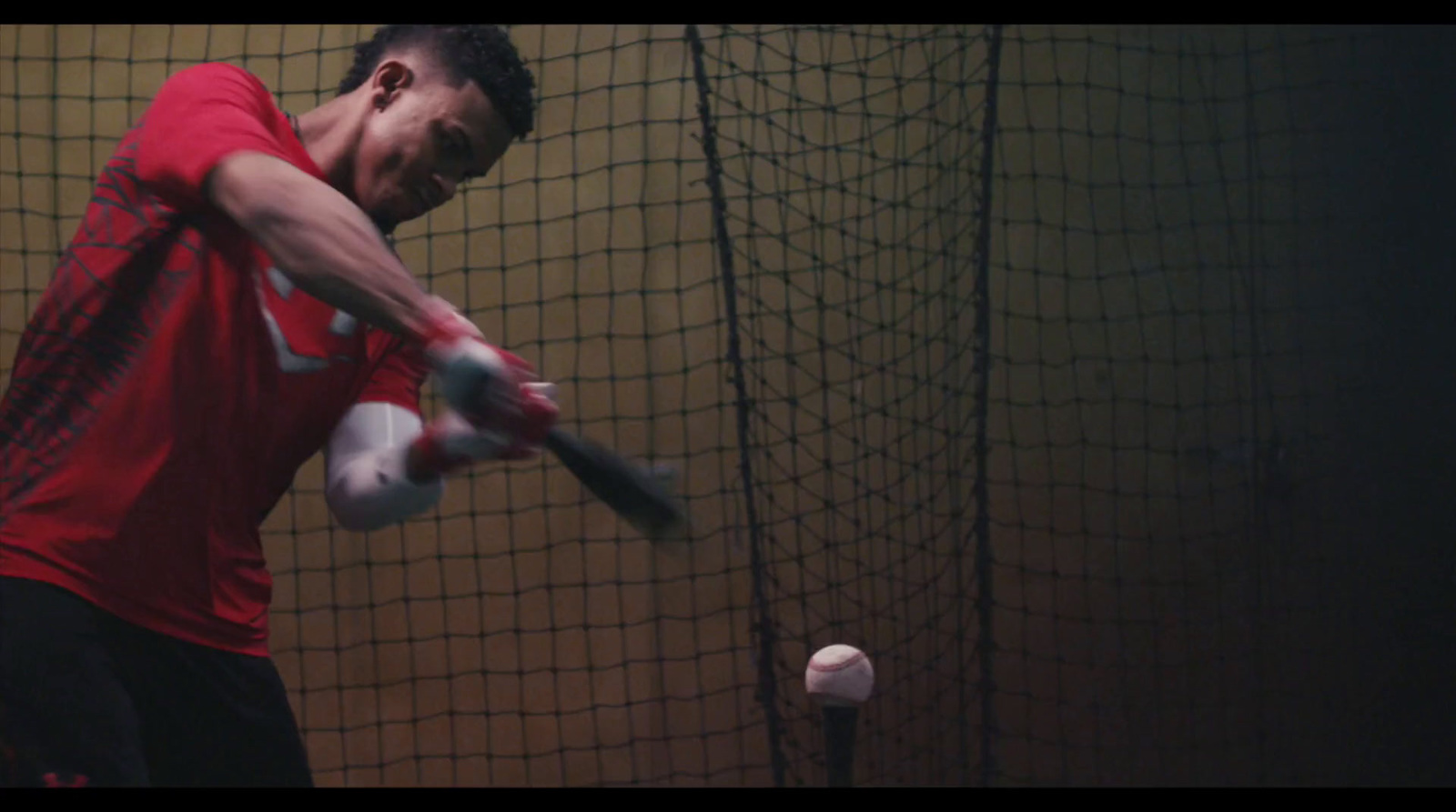 a man swinging a bat at a ball in a batting cage