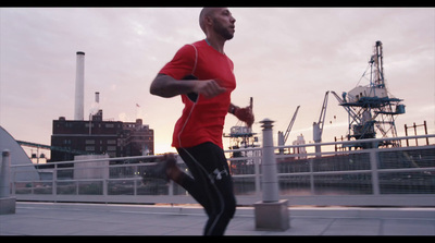 a man in a red shirt running on a bridge